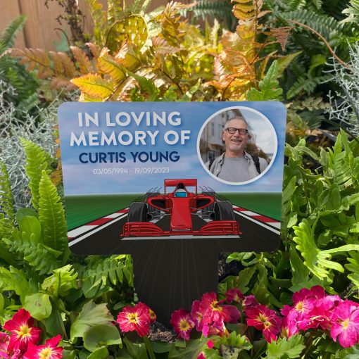 Formula One memorial stake inserted in flower bed surrounded by colourful flowers in the garden
