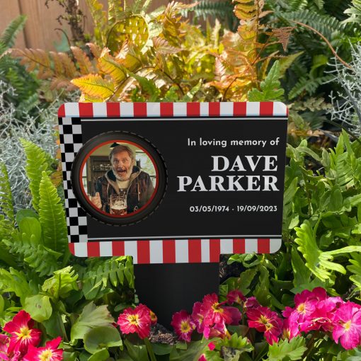 Racing track background with finish line and your chosen image inside a tyre memorial stake inserted in flower bed surrounded by colourful flowers in the garden